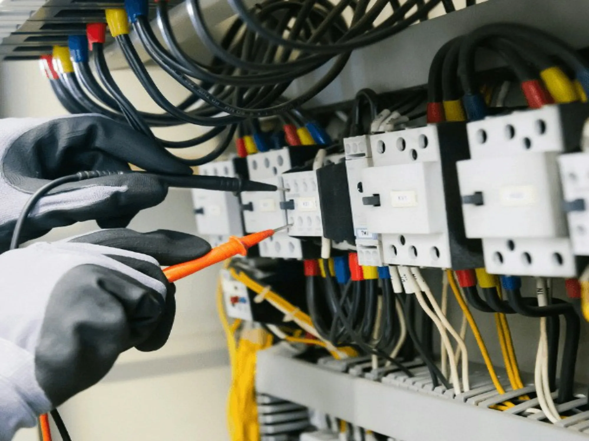 Electrician testing breakers with a probe in an open panel